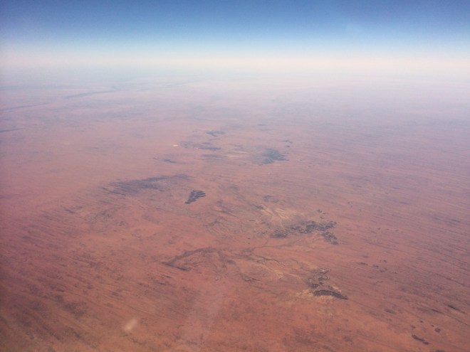 Parallel sand dunes and sporadic outcrops in arid central Australia. Taken from a jet plane.