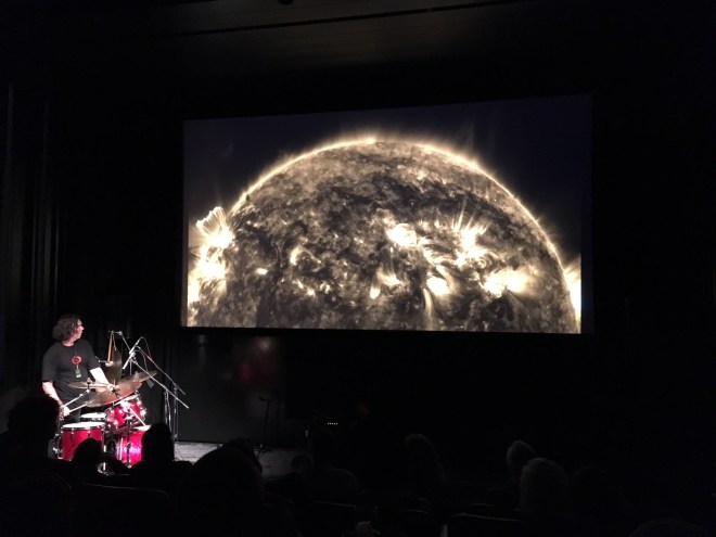 Konrad Park, creating improvised music in response to images of the sun. At one stage Konrad carried a cymbal around the room while playing it. The vibrations travelled through your body.
